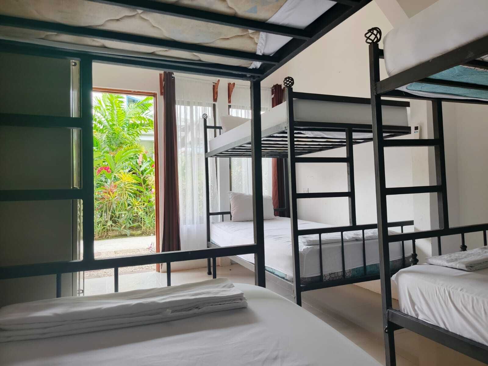 Un dormitorio con literas, una ventana con cortinas y vistas a zonas verdes.