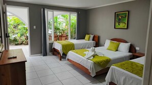 Habitación de hotel con dos camas, un escritorio y vista a zonas verdes por la ventana.