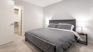 Een slaapkamer met een bed, een nachtkastje en een deur naar een andere kamer.