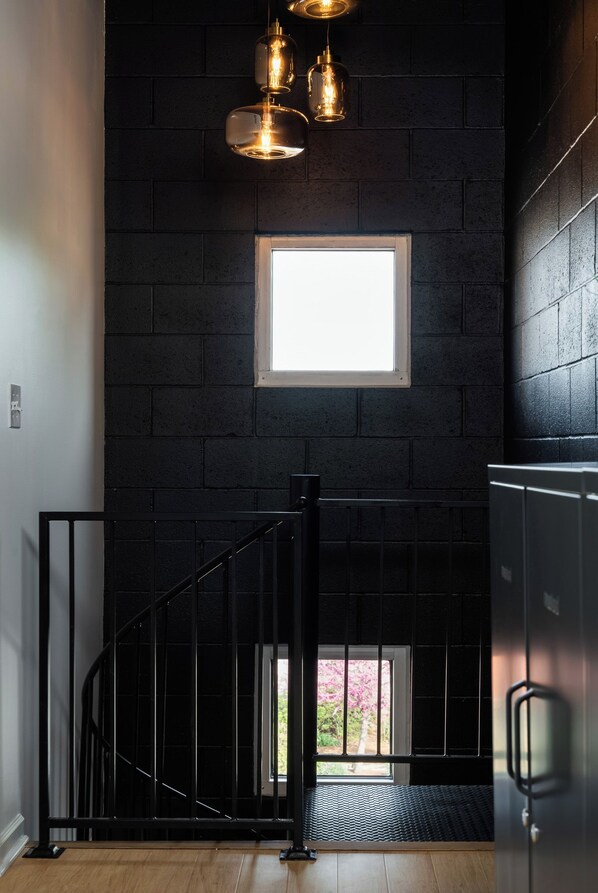 Uma escadaria com corrimão preto que leva a um patamar com janela e porta.