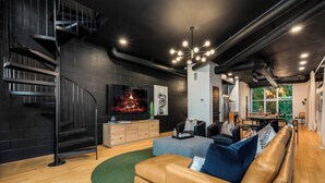Una sala de estar moderna con chimenea, una escalera y un comedor.