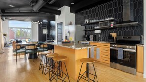 Una cocina moderna con una isla grande, taburetes de bar y un horno empotrado.
