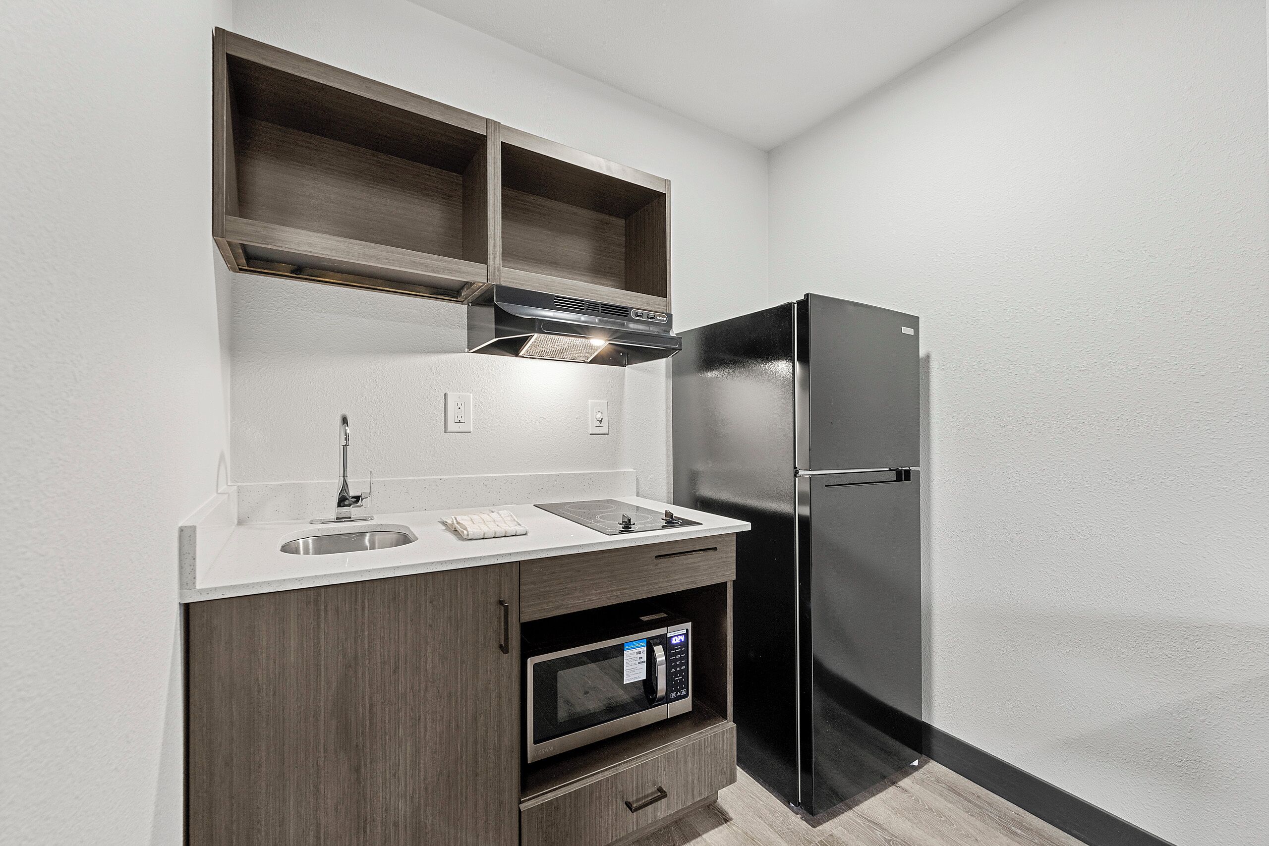 A compact kitchen with a built-in microwave, a stainless steel refrigerator, and a double sink.
