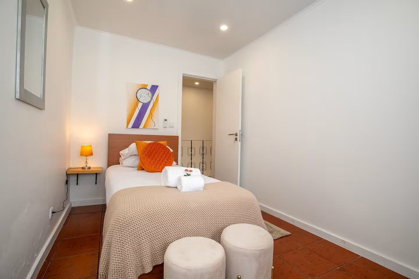 A hotel room with a bed, bedside lamp, and a wall-mounted clock.