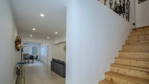 A staircase leading to a second floor with a modern interior, including a dining area and a sofa. - GuestReady - Villa Isla (Ponta Delgada)