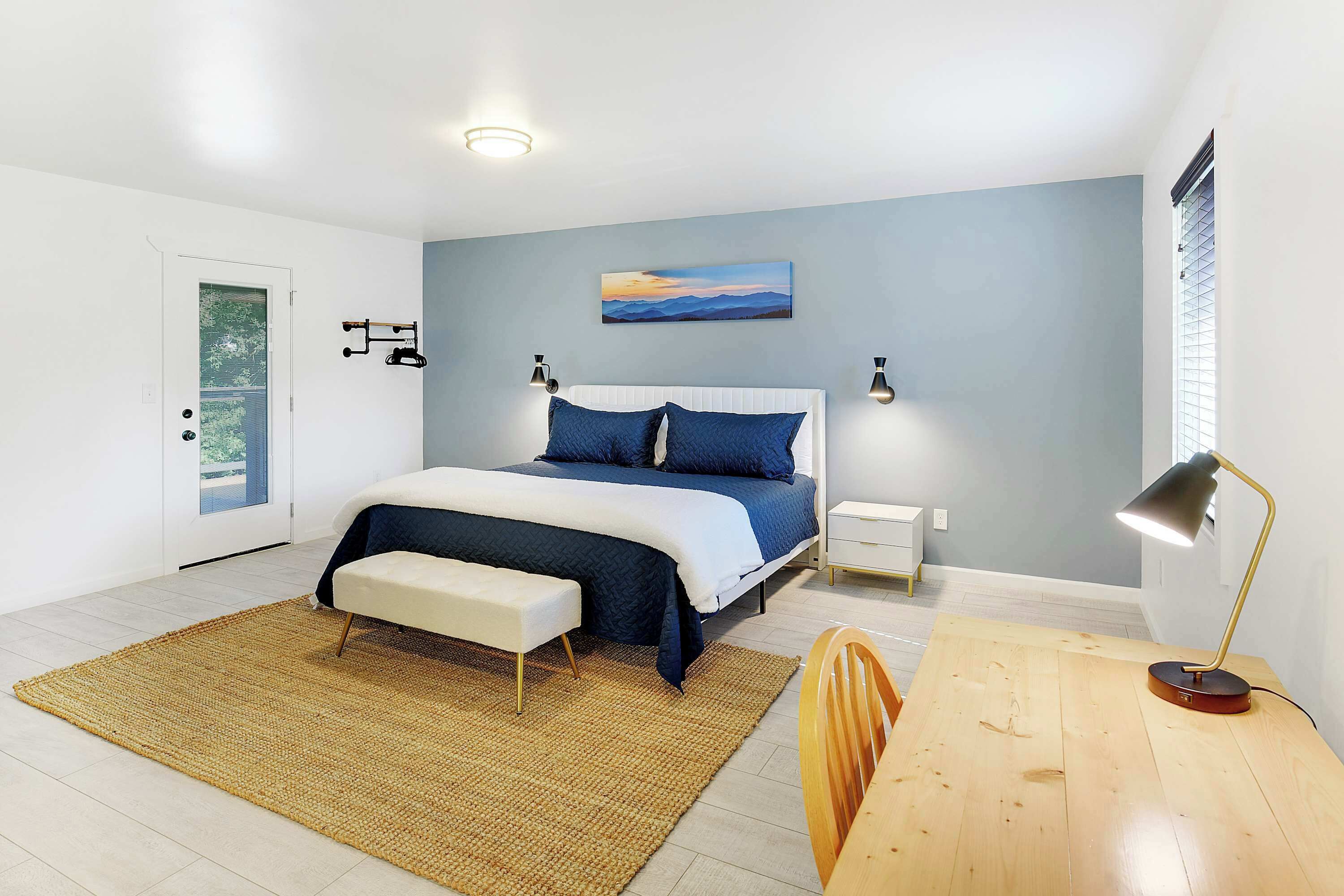 A modern bedroom with a bed, bedside tables, a desk, and a chair.