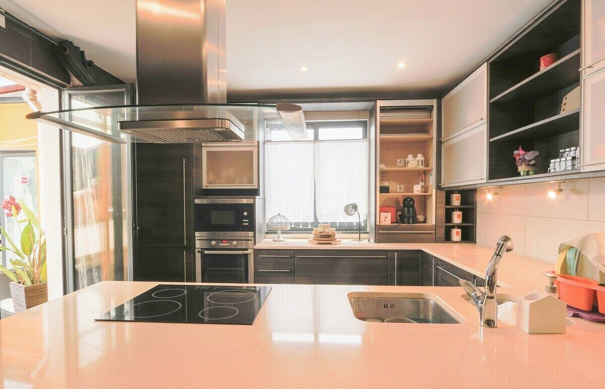 Une cuisine moderne dotée d’un îlot central, d’appareils électroménagers en acier inoxydable et de rangements intégrés.