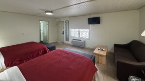 Une chambre d’hôtel avec deux lits, un canapé, une télévision, une fenêtre donnant sur un beau paysage et une petite table.