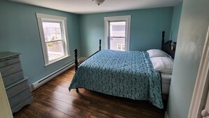 Une chambre à coucher avec un lit, une commode et deux fenêtres.