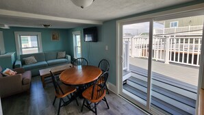 Un coin repas avec une table et des chaises en bois, un canapé et un téléviseur fixé au mur.