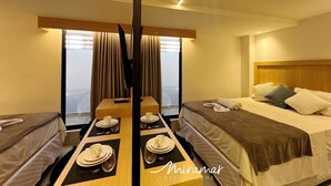 A hotel room with a bed, a dining table set with plates and cups, and a view through the window. - Legacy Suites (Joao Pessoa)
