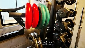 A gym with weightlifting equipment, including a bench press and various dumbbells. - Legacy Suites (Joao Pessoa)