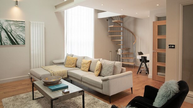 A modern living room with a sofa, coffee table, and a spiral staircase.