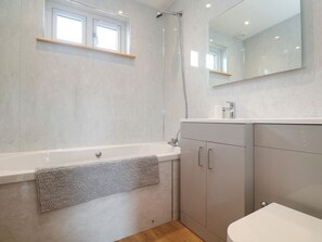 Ein modernes Badezimmer mit Badewanne, Dusche, Waschbecken und Spiegel.