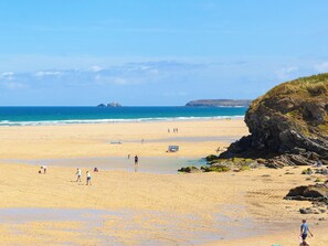 Une plage avec des gens, un phare et un paysage rocheux.