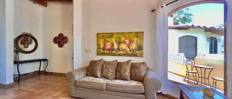 Una sala de estar con un sofá, una mesa de centro y un cuadro de fruta en la pared.