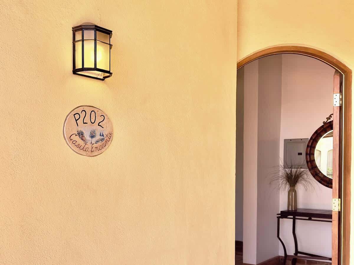 A wall-mounted light fixture and a circular sign with "P202" and "Casita Encantada" text.
