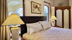 A neatly made bed with a headboard, two bedside lamps, and a framed artwork on the wall.