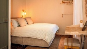 A bedroom with a bed, bedside lamps, a desk, and a chair. - The Tailor Shop. (Skibbereen)