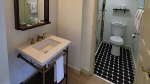 Un baño con un lavamanos blanco, un espejo y una zona de ducha.