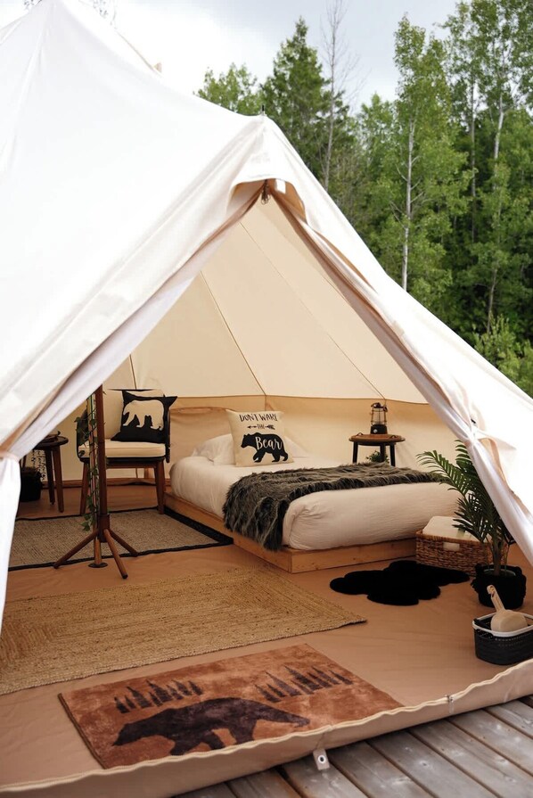 Ein Zelt mit Bett, Stuhl, kleinem Tisch und Lampe.