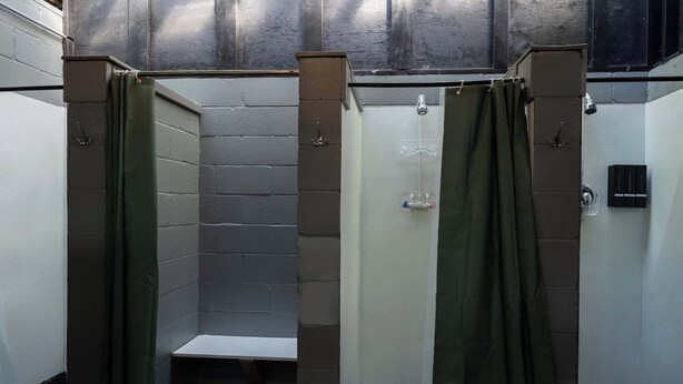 Een badkamer met twee douchecabines, elk met een douchekop en afvoer.
