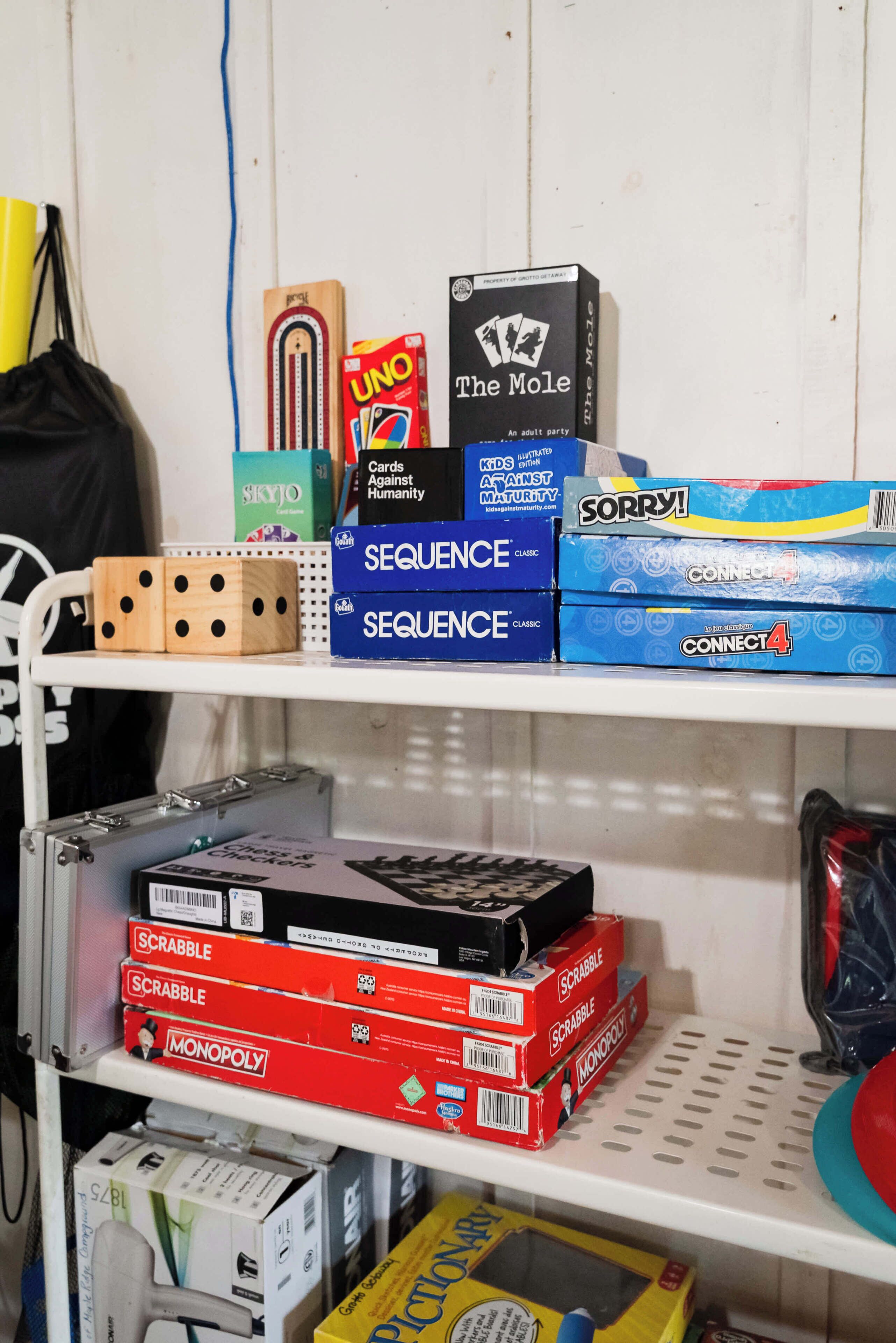A shelf with various board games including UNO, The Mole, Sequence, Sorry!, and Monopoly.