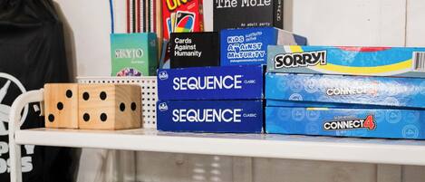 A shelf with various board games including UNO, The Mole, Sequence, Sorry!, and Monopoly.