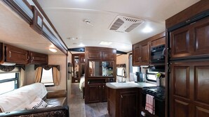A well-equipped RV kitchen with a central island, a stove, microwave, and a sink.