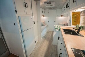 Una cocina compacta con gabinetes blancos, un refrigerador empotrado y un pequeño comedor.