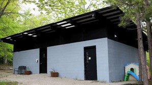 A building with a black roof and a blue exterior wall, a black door, and a small play area with a slide. - Explorer Glamping Nordic Spa Access Near Grotto (Miller Lake)