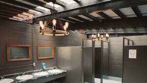 A restroom with marble sinks, wooden-framed mirrors, and exposed ceiling beams. - Explorer Glamping Nordic Spa Access Near Grotto (Miller Lake)