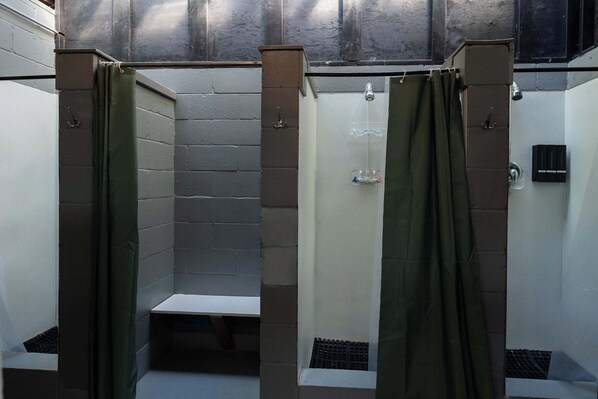 Een badkamer met twee douchecabines, elk met een douchekop en afvoer.