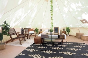 Una carpa con una mesa, sillas y plantas en macetas.