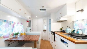 A compact kitchen with a wooden table, a stove, and a sink. - Blue Glamping RV w/ Nordic Spa Access near Grotto (Miller Lake)