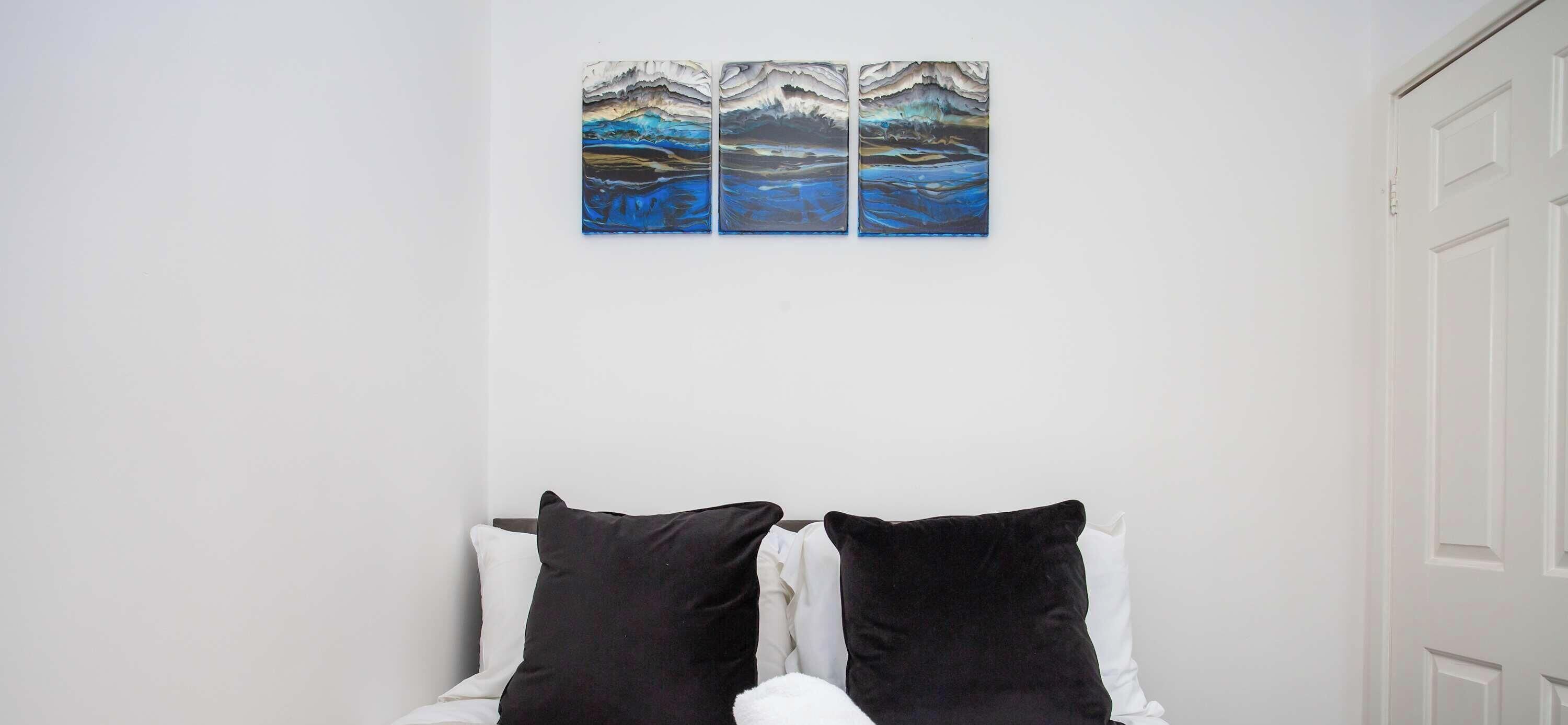 Ein Schlafzimmer mit einem Bett, zwei schwarzen Kissen und einer weißen Tür.