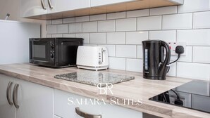 Eine moderne Küche mit weißen Schränken, einer Mikrowelle, einem Toaster und einer Kaffeemaschine.