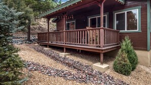 A wooden cabin with a covered porch, a gravel driveway, and a small evergreen tree. - Double Elk Lodge by Ruidoso Vacation Rentals (Ruidoso)