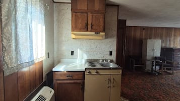 A compact kitchen with wooden cabinets, a stove, and a sink.