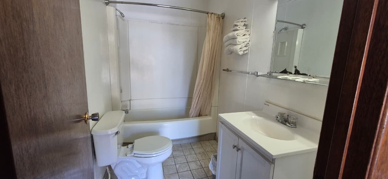 A bathroom with a bathtub, toilet, sink, and mirror.