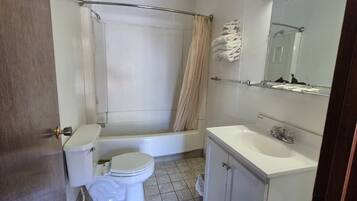 A bathroom with a bathtub, toilet, sink, and mirror.