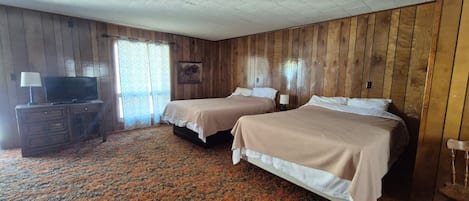 Ein Zimmer mit zwei Betten, einem Fernseher auf einer Kommode und einem gemusterten Teppich.