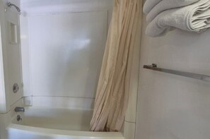 Une salle de bain équipée d’une baignoire, d’un porte-serviettes et d’un rideau de douche.