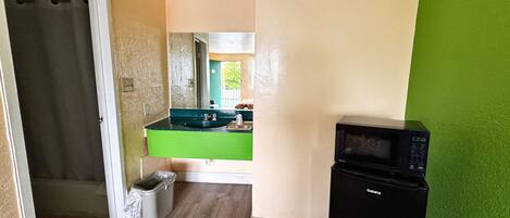 A compact kitchen with a black microwave, a green countertop, and a sink.