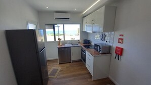 A compact kitchen with a refrigerator, sink, and microwave. There is a window providing a view of the outdoors. - Charming Rustic House in Nordeste surrounded by nature (Nordeste)
