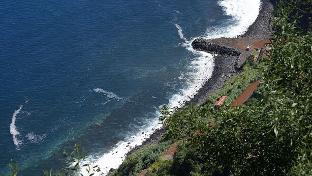 A coastal view with a rocky shoreline, clear blue water, and a path leading down to the beach. - Charming Rustic House in Nordeste surrounded by nature (Nordeste)