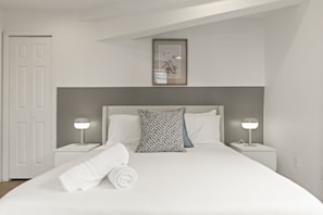 A bedroom with a bed, two bedside tables, a nightstand, a door, and a framed picture on the wall. - Chic 3BR Sleeps 6 Oasis | Near The Liberty Bell (Philadelphia)
