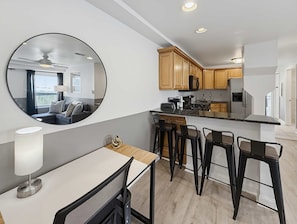A modern kitchen with a central island, bar stools, and a large mirror.