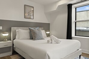 A neatly made bed with pillows, a bedside lamp, and a framed picture on the wall.