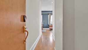 A hallway with a wooden door, a keycard reader, and a leather chair in the distance. - Charming 2BD by Independence Hall | Sleeps 6 (Philadelphia)